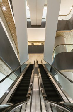 Bangkok, Tayland - 11 Ekim 2025 - modern bir binanın içinde metal parmaklıklı iki yürüyen merdivenin simetrik görüntüsü, biri yükselmek için, diğeri de inmek için. Mimaride temiz çizgiler, seçici odak.