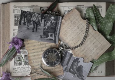 Bangkok, Tayland - 26 Ekim 2025 - Antika bir cep saati, metal zinciri eski bir nota kağıdına sarılı, antika bir düz-yatağın kalbinde duruyor. Etrafını saran siyah beyaz fotoğraflar evsizlerin dokunaklı hikayelerini yakalıyor. 