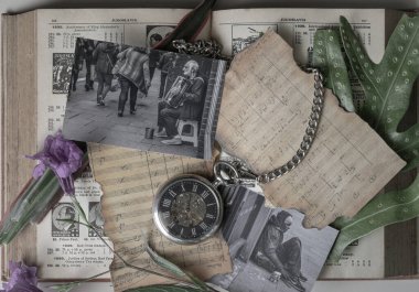 Bangkok, Tayland - 26 Ekim 2025 - Antika bir cep saati, metal zinciri eski bir nota kağıdına sarılı, antika bir düz-yatağın kalbinde duruyor. Etrafını saran siyah beyaz fotoğraflar evsizlerin dokunaklı hikayelerini yakalıyor. 