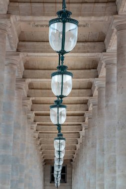 Fransa, Paris - Mayıs 03, 2025 - Palais-Royal Ulusal Malikanesi 'ndeki Onur Salonu' nun avlusunda, Tavandan sarkan Sütunlar ve Antika fenerlerle dolu koridor perspektifi. Duvar kağıdı, poster ve kopyalama alanı olarak kullan.