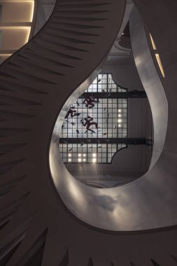 Fransa, Paris - Mayıs 03, 2025 - Fransa Ulusal Kütüphanesi 'nin (BnF) arka planında cam tavanlı zarif kıvrımlar ve karmaşık tasarım içeren büyük sarmal merdivenlerin altından görüntülenir. Duvar kağıdı, poster ve kopyalama alanı olarak kullan