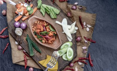 Kızarmış kaffir limon yapraklı domuz eti ezmesi ve ahşap arka planda taze sebzeler..