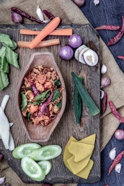 Kızarmış kaffir limon yapraklı domuz eti ezmesi ve ahşap arka planda taze sebzeler..