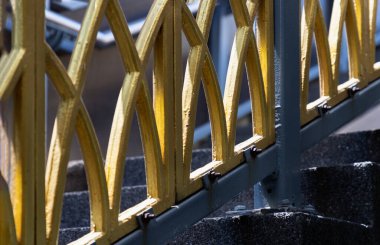 Birbirine kenetlenmiş kemerlerden oluşan bir kafes, parlak bir altınla tamamlanmış, bu endüstriyel bileşimin ana parçası olarak hizmet vermektedir. Işığın ve gölgenin etkileşimi her virajı ve kıvrımı ifade eder. Süslü tasarımı sağlam gri iskeleye dayandırır.