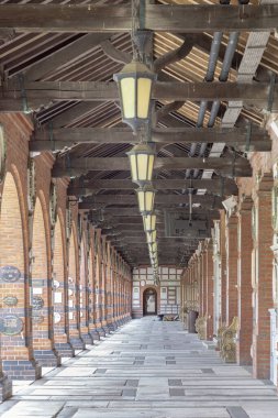 Londra, İngiltere - 08 Mayıs 2025 - Kapalı bir yürüyüş yolu manastırı geniş perspektiften inceleniyor, karmaşık bir şekilde detaylı koyu ahşap kirişli tavan ve Golders Green Krematoryumu 'nun geleneksel, eski dünya tarzı fenerlerini ortaya çıkarıyor.