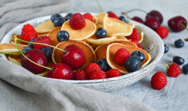 Krep gevreği, içinde yabanmersini, ahududu ve kiraz olan bir kasede mini krep. Sağlıklı beslenme. Mutfak trendi. Ev yapımı yemek..