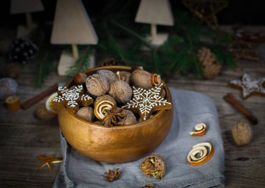 Ladin dallarının Noel kompozisyonu, bir kase fındık, tarçın, anason, ahşap arka planda zencefilli kurabiye. Geçmişi. Doğal renkler. Yeni yıl tatili kavramı. El yapımı.