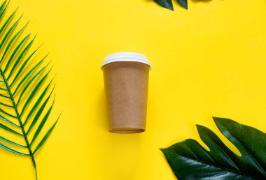 Çevre dostu kağıt camlar, kokteyl tüpleri, sarı arka planda tropik yapraklar. Sıfır atık, plastiksiz konsept.