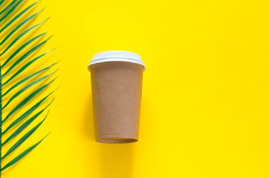 Çevre dostu kağıt camlar, sarı arka planda tropik yapraklar. sarı arkaplanda.