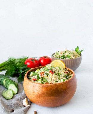 Beyaz mermer arka planda kuskus veya bulgur içeren geleneksel doğu salatası Tabouleh.