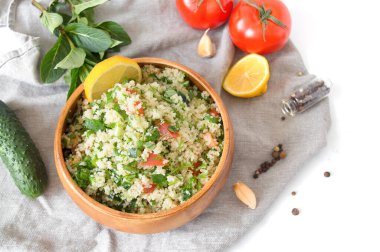 Beyaz mermer arka planda kuskus veya bulgur içeren geleneksel doğu salatası Tabouleh.
