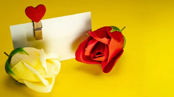 Postcard for congratulations. Roses. Red heart on a clothespin on a bright yellow background. Happy Valentine\'s Day greetings. Place for text.