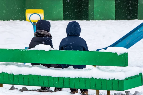 Два Мальчика Разговаривают Скамейке Снежной Детской Площадке Концепция Грусти Одиночества — стоковое фото