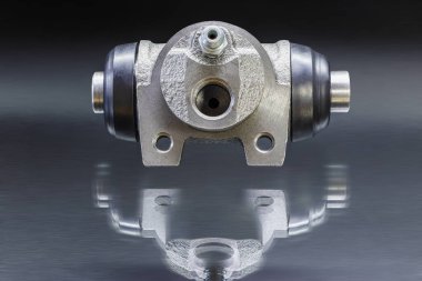 Fren hidrolik silindirli fren davulu. Yüzeyde siyah arka planda yansımaları var. Silindir kıçlı, debriyaj ustası. Fren silindiri, frenlemede çalışması için tasarlanmıştır.