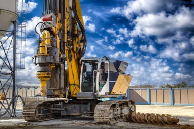 Mavi bulutlu gökyüzüne karşı hidrolik sondaj kulesi. Delme yoluyla sıkılmış yığınların kurulumu. Vakıflar ve vakıflar. Toprağı eşeliyorlar.