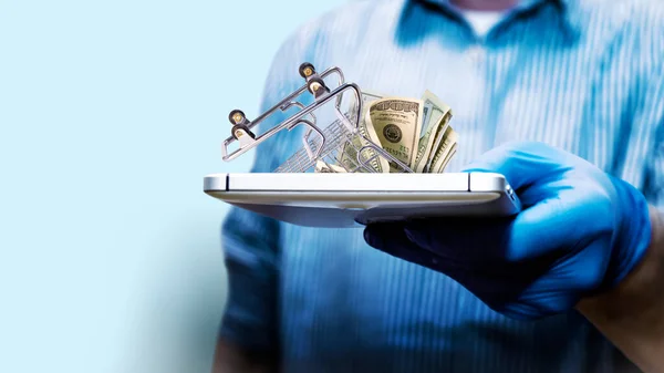 A man holds a tablet with an inverted basket from a hypermarket. Online shopping. The concept of delivery of goods in crisis. Blurred background. Copy space