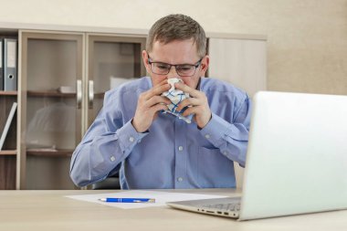 Ofis masasında burnunu silen olgun bir iş adamı. Soğuk bir ofis çalışanı burnunu mendile sümkürdü. İş yerinde soğuk ve hastalık. Alerji