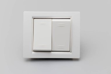 Gri arka planda iki düğmeli beyaz düğme. Tamir için ev elektrikçisi. Enerji tasarrufu kavramı. Yakın plan. Tam odaklanma. Boşluğu kopyala
