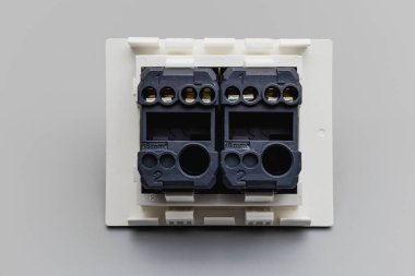 Gri arka planda iki düğmeli beyaz düğme. Tamir için ev elektrikçisi. Enerji tasarrufu kavramı. Yakın plan. Tam odaklanma. Boşluğu kopyala