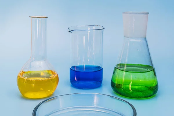 Trzy Szklane Kolby Laboratoryjne Roztworami Żółtego Zielonego Niebieskiego Delikatnym Niebieskim — Zdjęcie stockowe