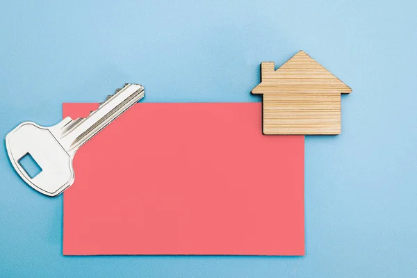 The concept of mortgage, sale and rental of housing and real estate. Business card with a key to the apartment and a mock-up of a wooden house. Copy space. Mock-up
