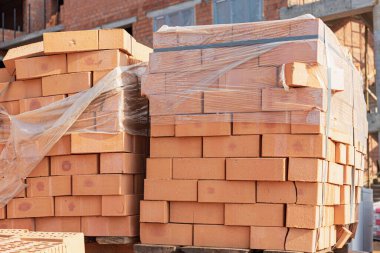 Bir inşaat alanında paletlerin içinde tuğlalar. İnşaat malzemeleri. Ev yapmak için kırmızı tuğla