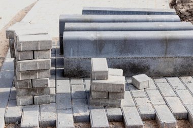 Asfalt tamiri ve kaldırım taşlarının döşenmesi, arka planda fayans küplerinin istiflenmesi. Şehrin yaya bölgesine kaldırım döşeme döşemesi, kum dolgu. Yol fayansları ve kaldırımlar