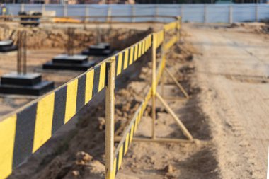 İnşaat çiti eskrimi. İnşaat güvenliği. Koruyucu çitlerle güçlendirilmiş beton temellere sahip inşaat sahası