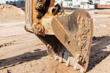 Kazı kovası kapanıyor. İnşaat alanında ve yol inşaatında kazı çalışmaları. İnşaat makineleri