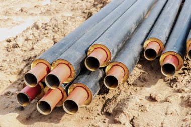 İnşaat alanındaki bir siperde ısıtma boruları döşemek. Enerji tasarruflu yalıtılmış borular. Soğuk ve sıcak su, evin ısıtma ve ısıtma sistemi.