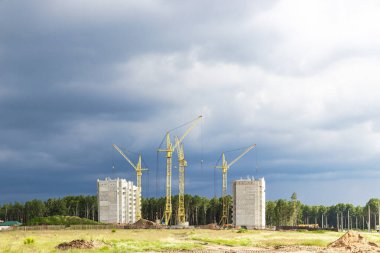 Günbatımı gökyüzünün arka planına karşı kule vinçlerinin çalışması. Modern konut inşaatı. Endüstri mühendisliği. Konut kredisi inşaatı