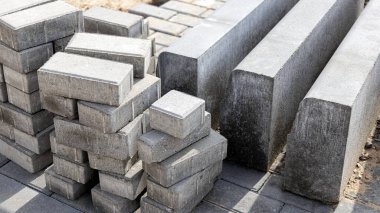 Asfalt tamiri ve kaldırım taşlarının döşenmesi, arka planda fayans küplerinin istiflenmesi. Şehrin yaya bölgesine kaldırım döşeme döşemesi, kum dolgu. Yol fayansları ve kaldırımlar