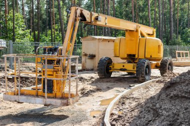 Erkeğin işi çok yüksektir. İşçileri inşaat alanındaki yüksekliğe çıkarmak için kendi kendine çalışan bir inşaat mekanizması. Tepede iyi iş çıkardın.