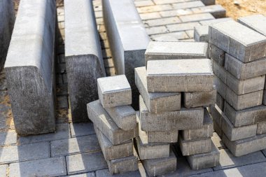 Asfalt tamiri ve kaldırım taşlarının döşenmesi, arka planda fayans küplerinin istiflenmesi. Şehrin yaya bölgesine kaldırım döşeme döşemesi, kum dolgu. Yol fayansları ve kaldırımlar