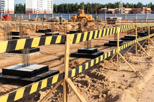 İnşaat çiti eskrimi. İnşaat güvenliği. Koruyucu çitlerle güçlendirilmiş beton temellere sahip inşaat sahası