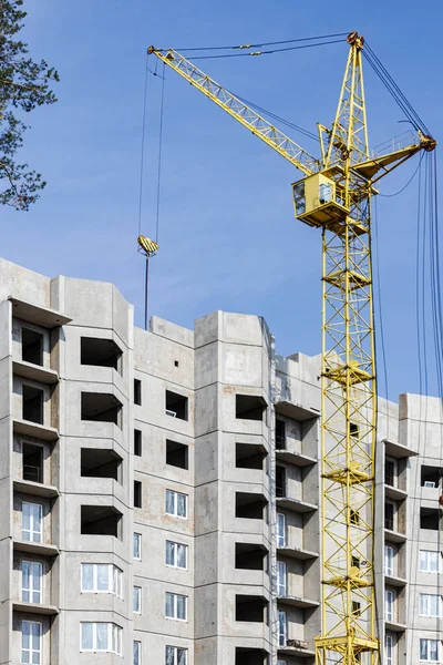 The work of a tower crane during the construction of a panel house made of reinforced concrete. Modern housing construction for young families. Industrial engineering. Construction of mortgage housing