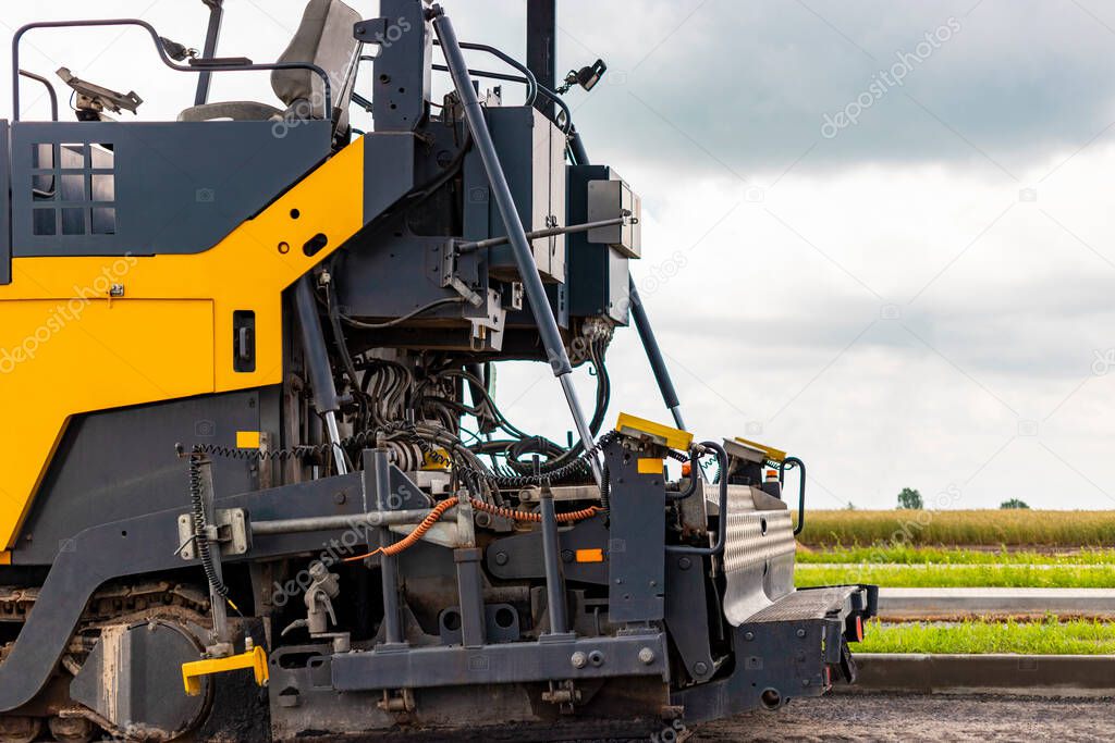 Asphalt paving equipment. Asphalt paver and heavy vibratory roller. Construction of new roads and road junctions. Heavy construction industrial machinery