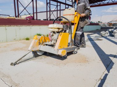 İnşaat alanında çalışan bir işçi elmas testeresiyle beton kesiyor. Beton kırıcı. Genişleme eklemleri aygıtı