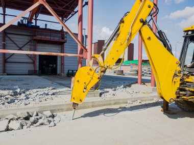 Hidrolik çekiçle kazıcıyla güçlendirilmiş betonun sökülmesi. Ağır inşaat ekipmanları kullanılarak güçlendirilmiş beton donanımı. Binaların yıkılması