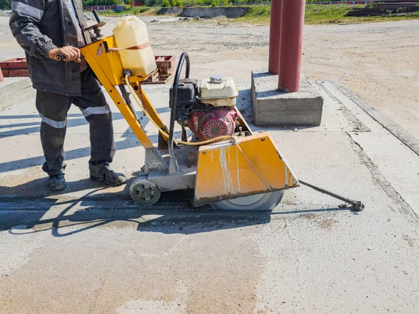 İnşaat alanında çalışan bir işçi elmas testeresiyle beton kesiyor. Beton kırıcı. Genişleme eklemleri aygıtı