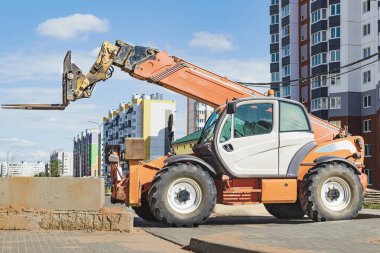 Modern bir yerleşim alanının şantiyesinde teleskopik direkli güçlü bir tekerlek forklifti. Yükleri kaldırmak ve taşımak için inşaat ekipmanları