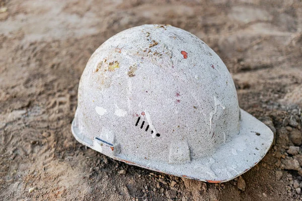 Dirty old work helmet left on the ground of construction site