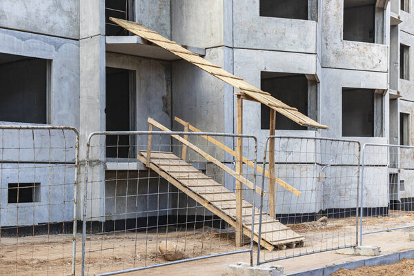 Construction of a multi-storey panel reinforced concrete house. Safe ramp at the entrance to the building. Construction site safety