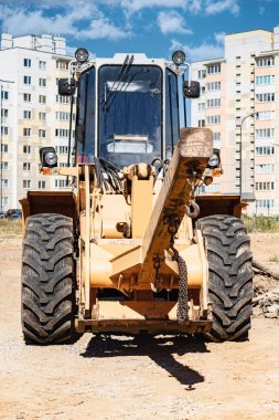 Modern bir yerleşim alanının şantiyesinde ağır malları taşımak için güçlü bir tekerlek yükleyici. Yükleri kaldırmak ve taşımak için inşaat ekipmanları