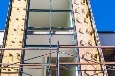 Binanın yeniden inşası sırasında tahta güvertelerle iskeleler ve iskeleler. Yükseklerde inşaat işi yapıyor. İnşaat güvenliği