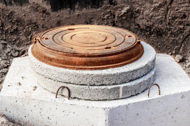 Beton bir kuyuya metal bir kapı döşemek. Yakın plan. Yol çalışıyor. Yeraltı tesislerinin ve kuyularının korunması