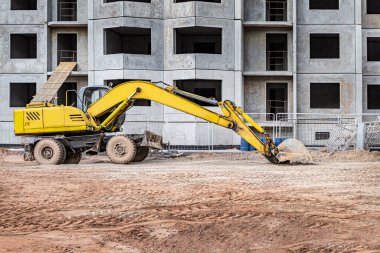 Büyük bir kova ile ağır bir sürüngen kazıcısı inşaat halindeki bir panelin önünde çalışmaya hazırlanıyor. Toprak işçiliği için ağır inşaat malzemeleri. Taş ocağı kazıcısı