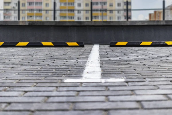 Arabalar için sarı park yerlerinin olduğu bir yerleşim bölgesinde boş bir otopark. Yakın plan. Park Limiter 'ını Durdur