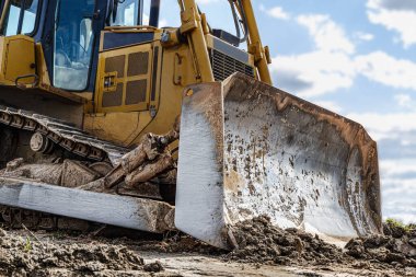 Buldozer makinesi inşaat alanını yerle bir ediyor. Tırtıllı toprak taşıyıcı toprağı hareket ettiriyor. Yakın plan. İnşaat ağır makineler