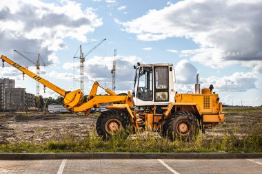 Modern bir yerleşim alanının şantiyesinde ağır malları taşımak için güçlü bir tekerlek yükleyici. Yükleri kaldırmak ve taşımak için inşaat ekipmanları